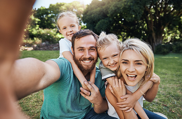 family taking a joyful selfie in a park with two kids enjoying fun together 4 memories 4 happiness