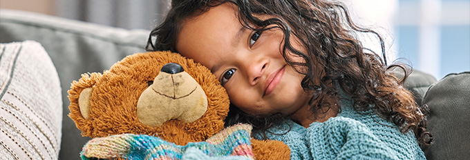 girl hugging teddy bear smiling cozy home childhood joy eight years old