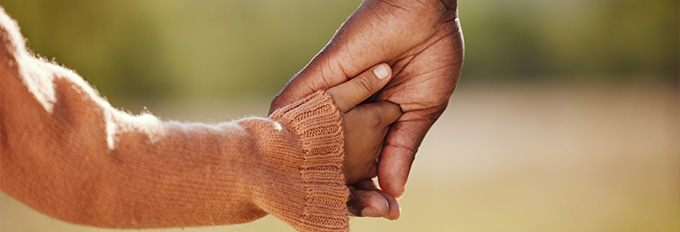 adult hand holding child's hand with warm sweater in soft background showing connection and care for five important moments