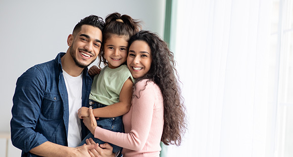 smiling family with two children in a bright room wearing casual clothing