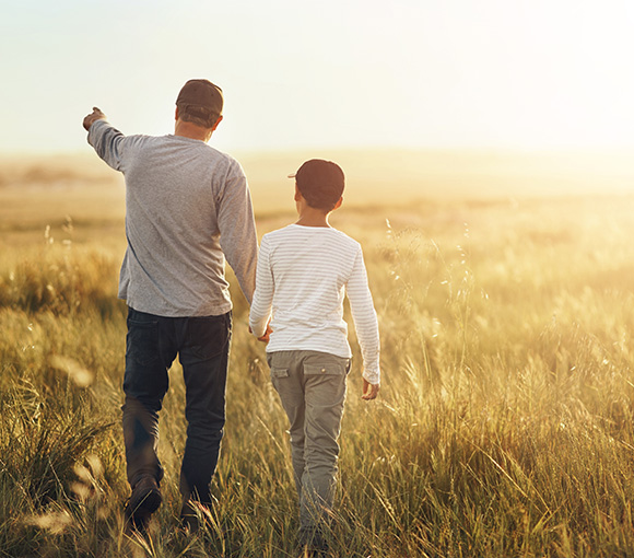 man and boy walking in a field during sunset exploring nature together and creating memories with 2 generations